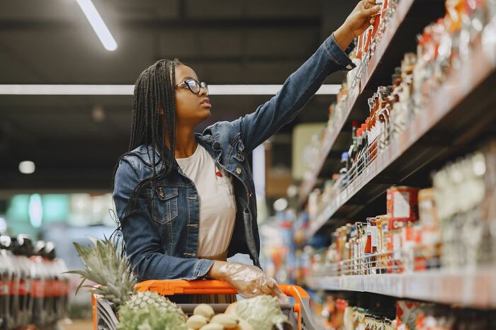 A woman shopping for groceries in a supermarket, using clever life tricks to save money on food