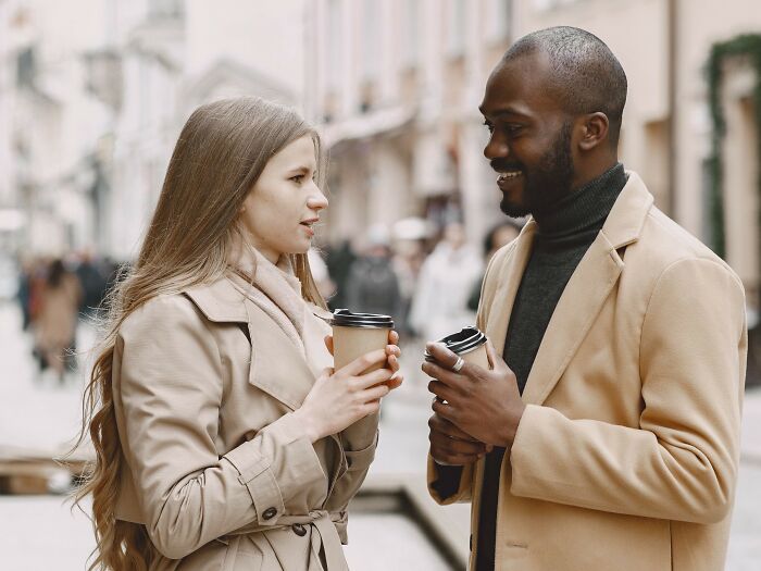 Woman and man talking with coffee cups in street discussing microaggressions women hear
