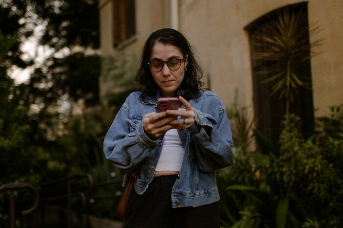Woman looking at her phone, reflecting a funny instance of an embarrassing fail.
