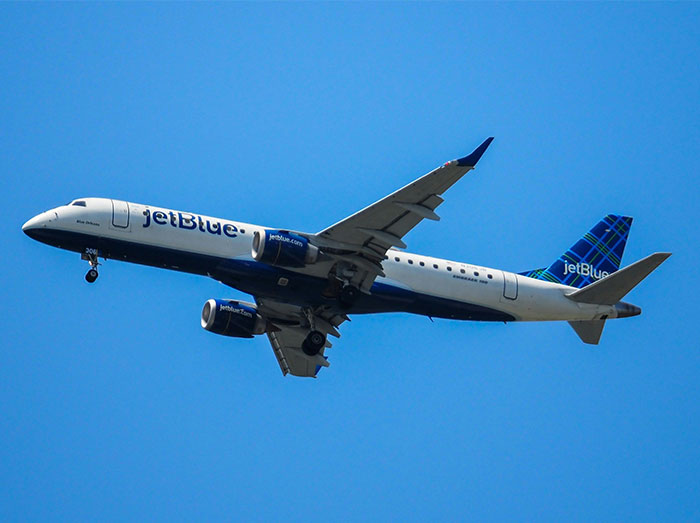 A JetBlue airplane flying in the sky representing a mid-flight incident