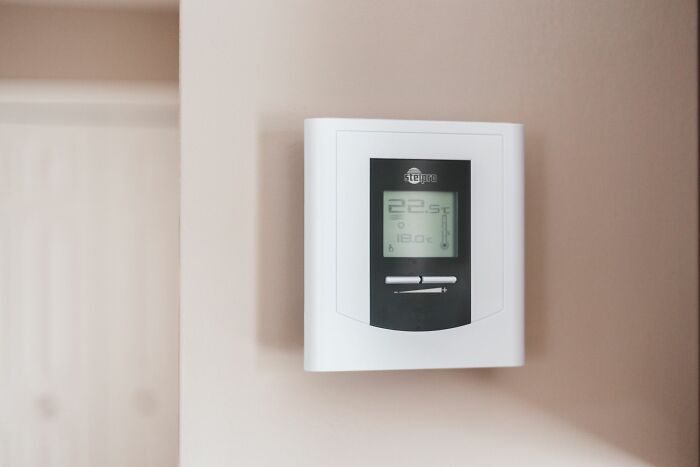 Wall-mounted digital thermostat displaying temperature