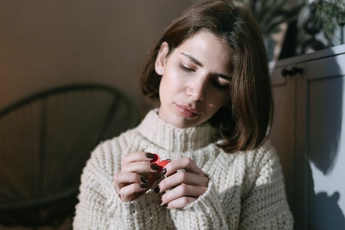 A sad woman looking down at a small object, contemplating why men walked away from their marriage.