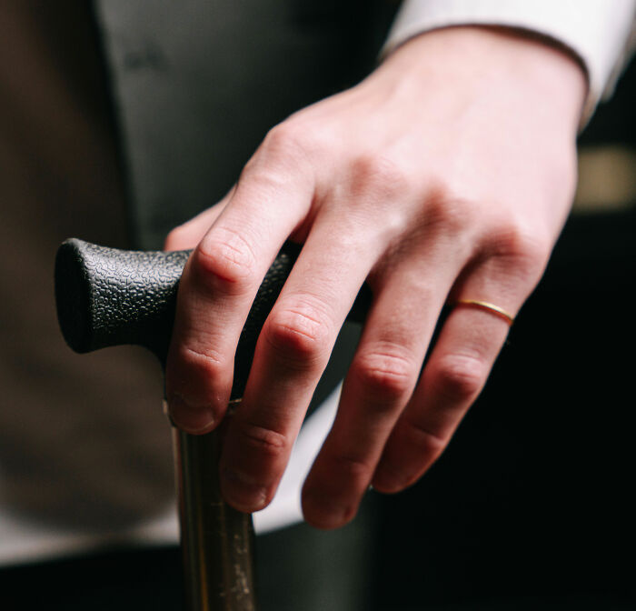 A hand gripping a walking stick, illustrating young people relying on mobility aids