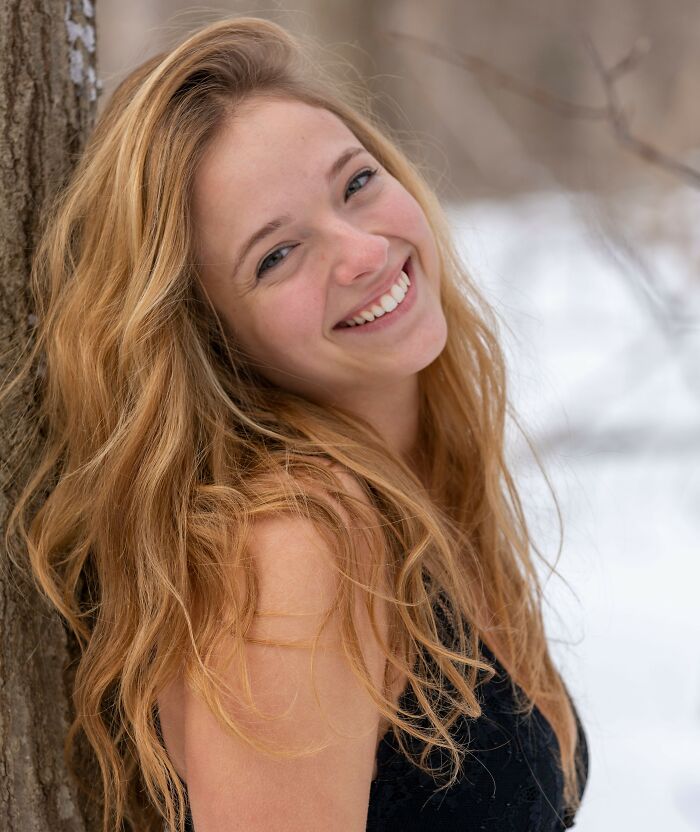 Smiling blonde woman leaning against a tree outdoors. Life lessons and things women wish they knew.