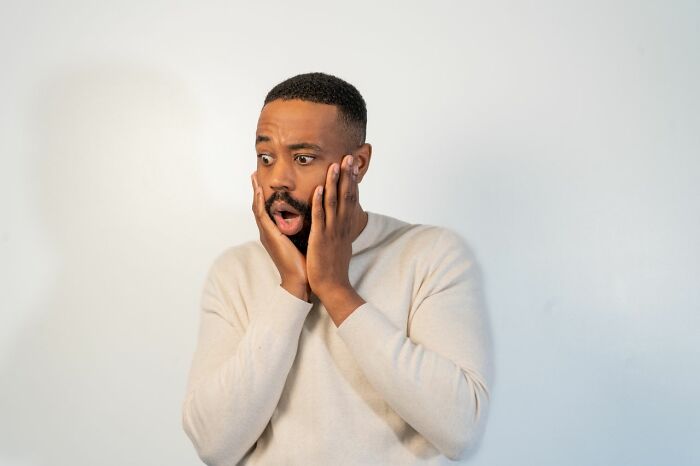 A shocked man with hands on his face, reacting to an urgent feeling or frightening news