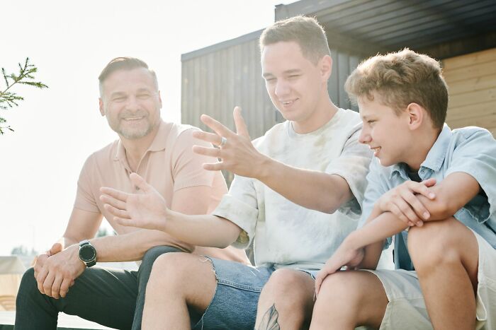 A happy father and his two sons talking outside, symbolizing men who cherish family over a walked away marriage.
