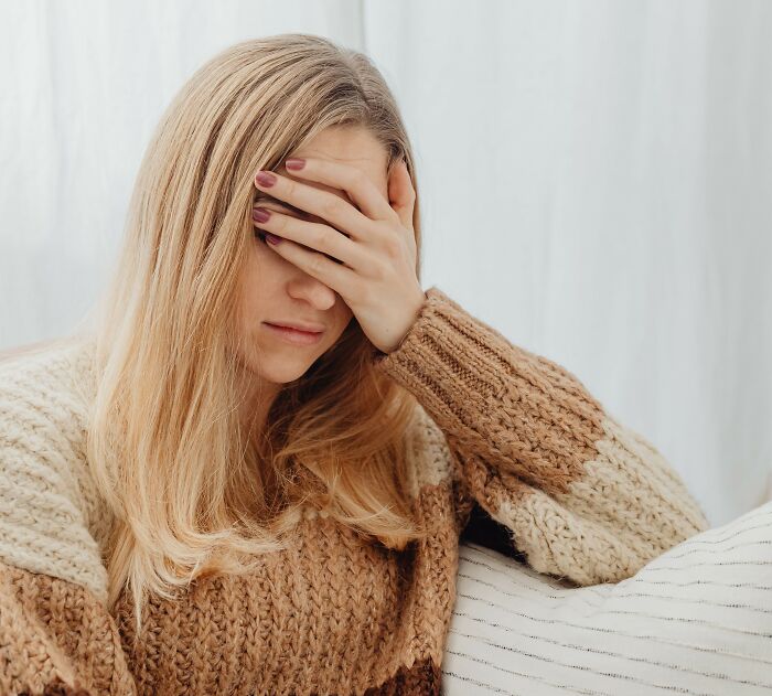 A woman covering her face with her hand, depicting chilling stories of people sensing something off.