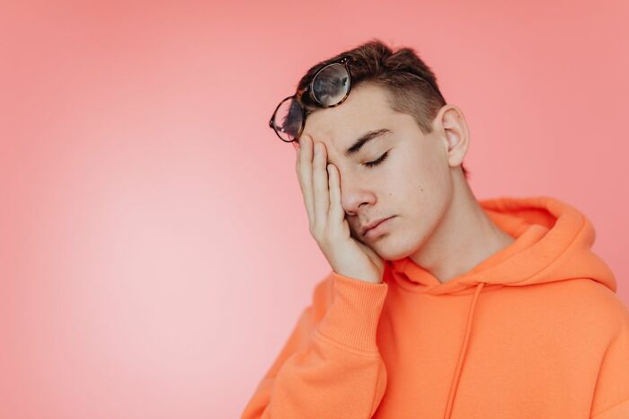 Embarrassed teen in orange hoodie recalling Karen experiences