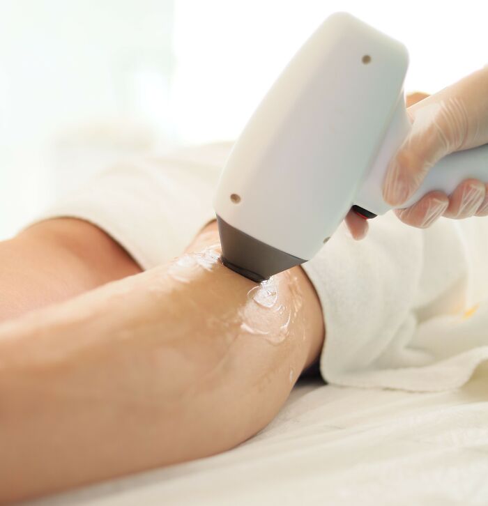 A woman undergoes laser hair removal treatment on her leg.