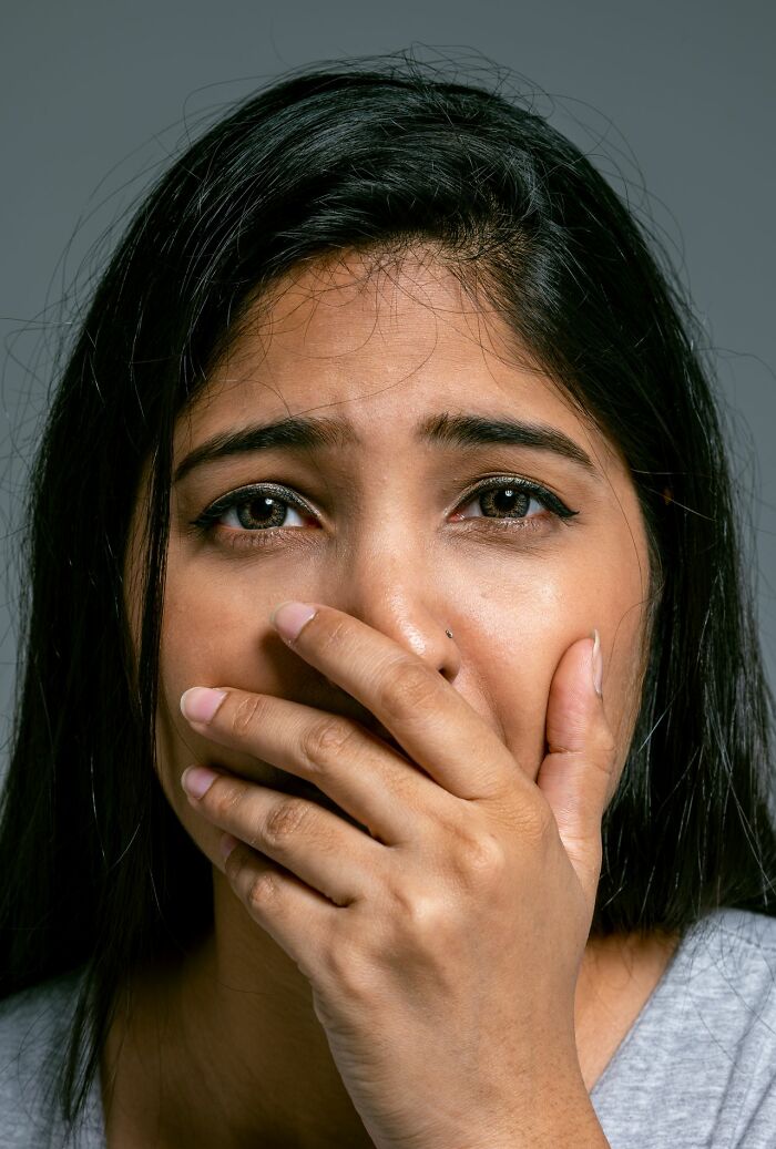 A worried woman covering her mouth in fear, evoking an urgent feeling to leave immediately