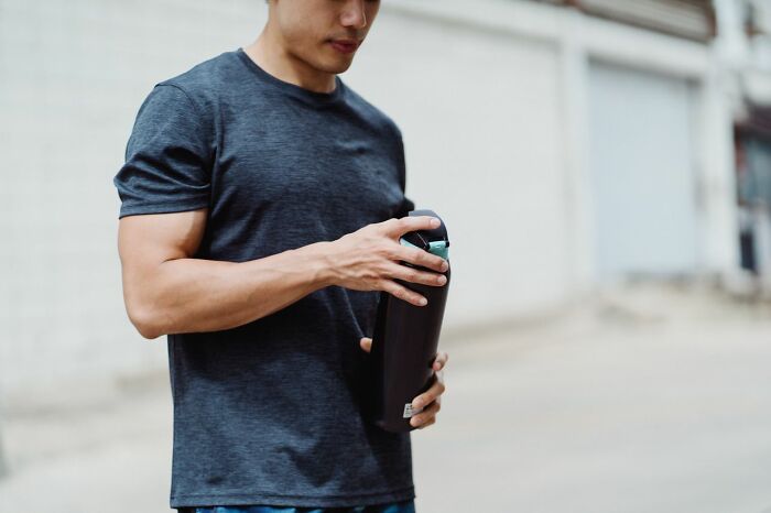 Man opening a modern water bottle, demonstrating clever life tricks for daily hydration and fitness.
