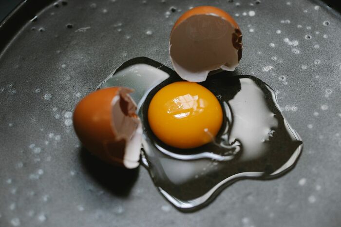 A cracked raw egg with yolk on a dark surface instead of candy while trick-or-treating.