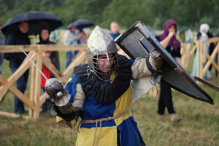 A knight in full armor holding a sword and shield, depicting realistic combat often misrepresented by Hollywood.