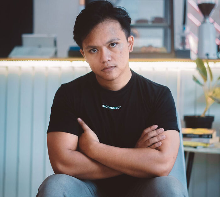 A man sitting with crossed arms indoors, representing satisfying revenge stories.