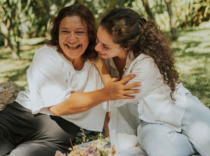 Two women smiling together outdoors, fitting themes of karma and satisfying revenge stories.