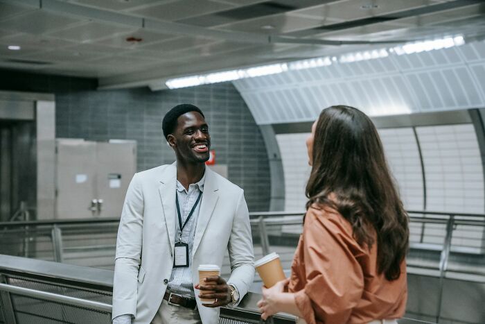 Two coworkers talking and laughing in a modern subway, unlike Hollywood drama.