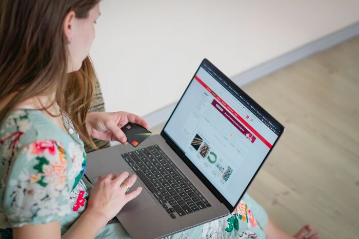 A woman holding a credit card and shopping online, illustrating clever life tricks for saving money