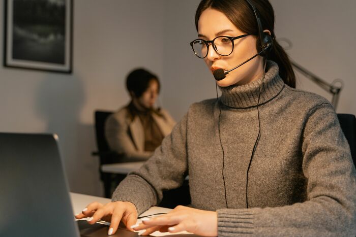 A woman wearing a headset with a mic working on a laptop, illustrating unethical life pro tips