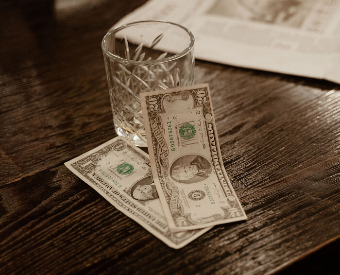 Cash money on a wooden table, representing a tip left at a California bar.