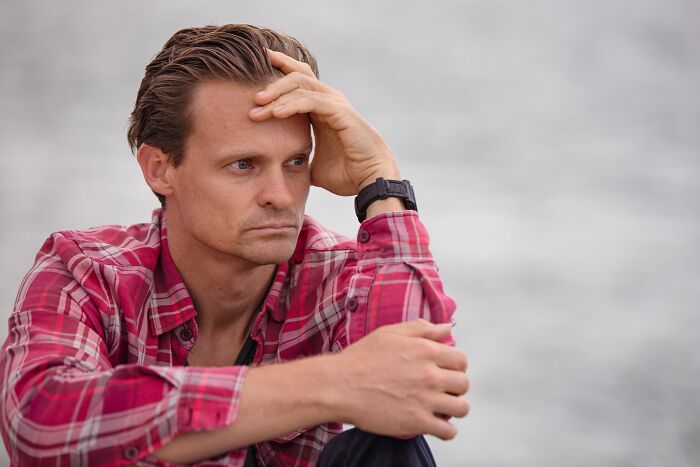 A man in a plaid shirt looking thoughtful and anxious as he keeps secrets.