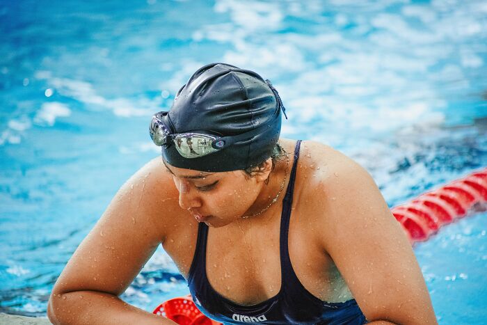Female swimmer in black swim cap preparing in pool with microaggressions theme