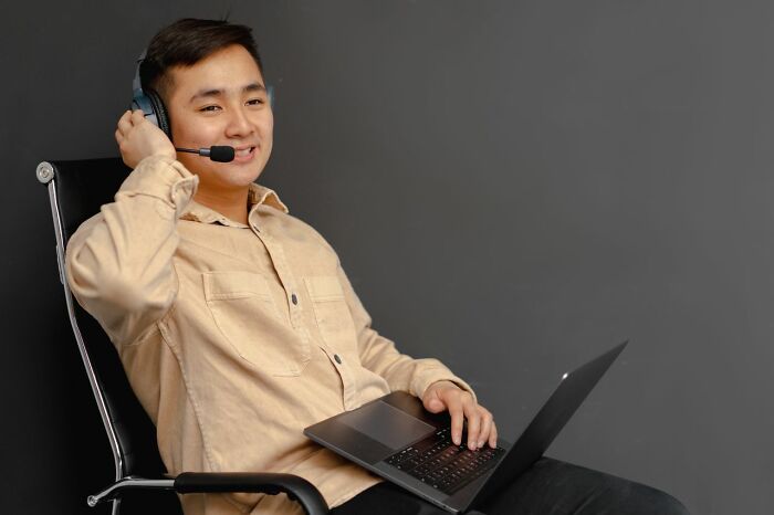 A man with a headset working on a laptop, showing clever life tricks for remote work and communication