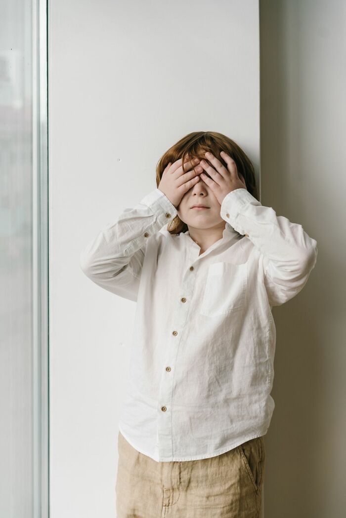 Child covering eyes in embarrassment representing kids growing up with Karens