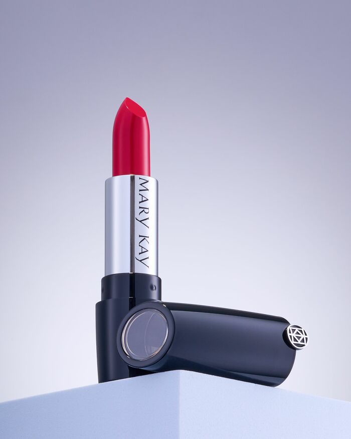 Red Mary Kay lipstick tube standing on a blue pedestal, representing cosmetics companies consumers choose to boycott