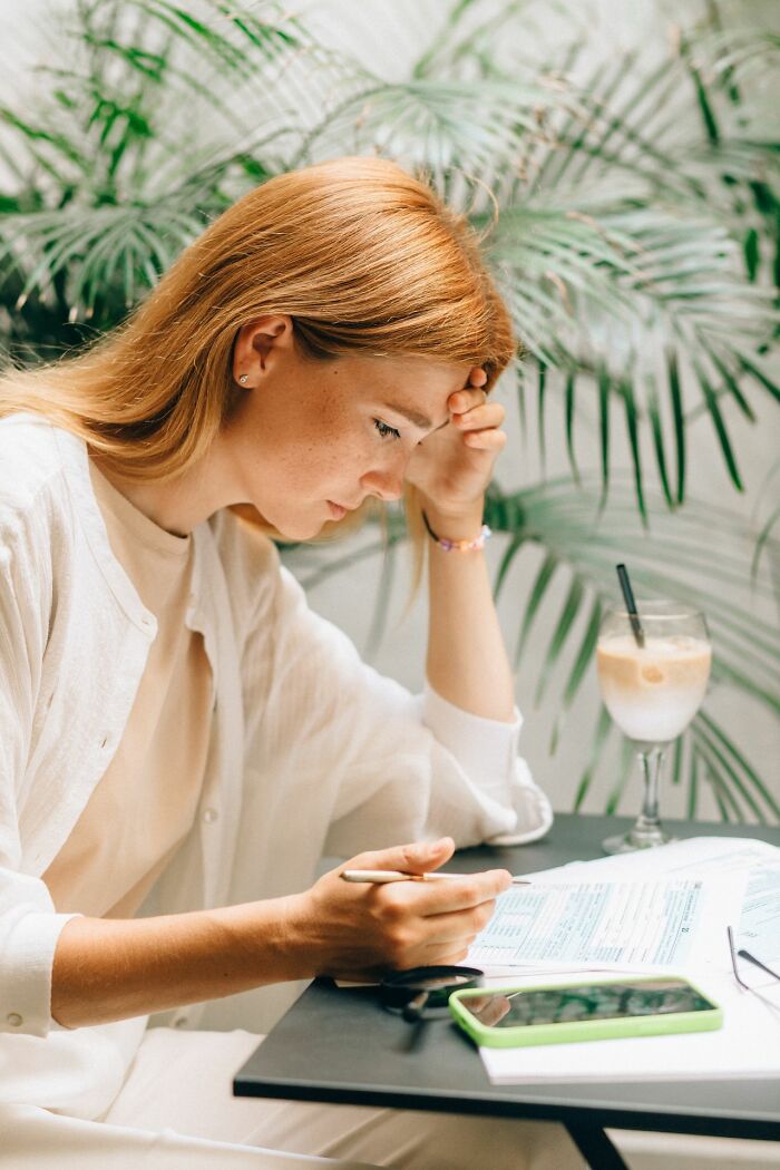 A stressed woman reviewing paperwork at a desk, applying clever life tricks for personal finance