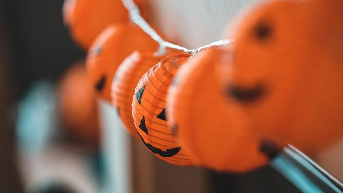 A string of illuminated pumpkin lanterns hanging indoors, symbolizing unethical life pro tips for festive occasions