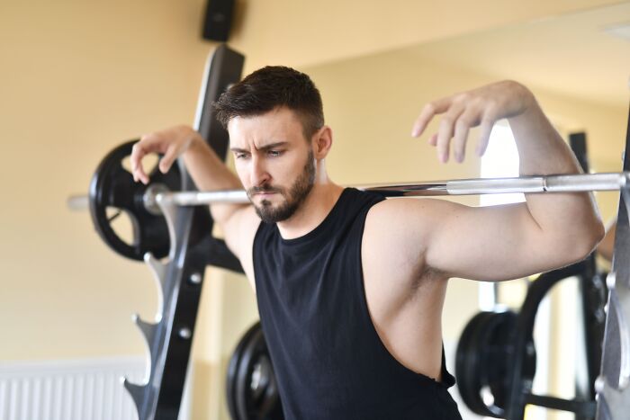A tired man at a gym squat rack, illustrating how professionals lose trust from clients.