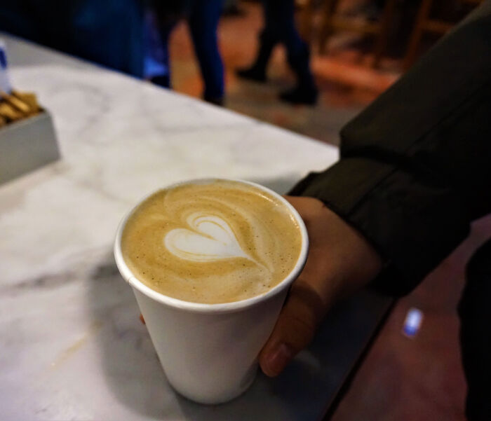 Close-up of a warm coffee with heart latte art enjoyed after a husband breaks 5 of wife's ribs by giving her a hug.