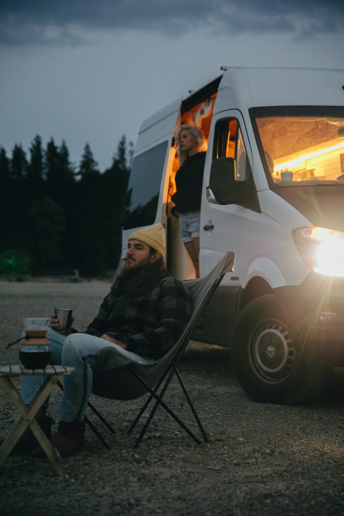 Man sitting outside camper van at dusk, a situation evoking an urgent feeling to leave immediately