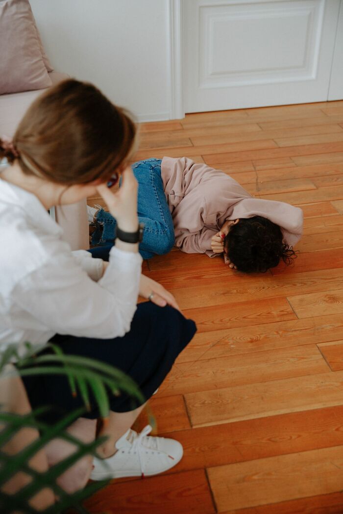 Child upset on floor with adult concerned in Karen-related story
