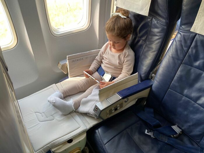 A young kid sitting in a comfortable airplane seat during family flights