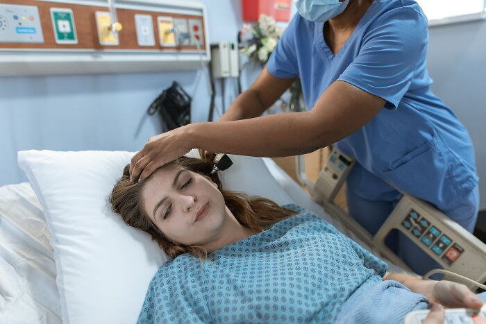 A healthcare professional examining a patient in a hospital bed, showing doctor-client trust.