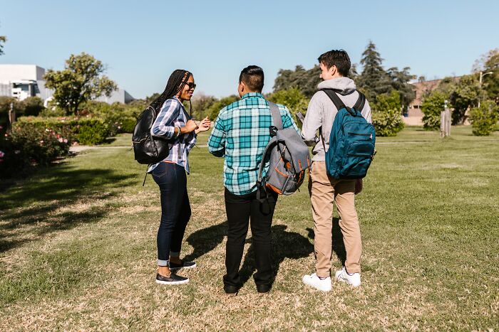 Three students with backpacks walking on campus, depicting unethical life pro tips for college.