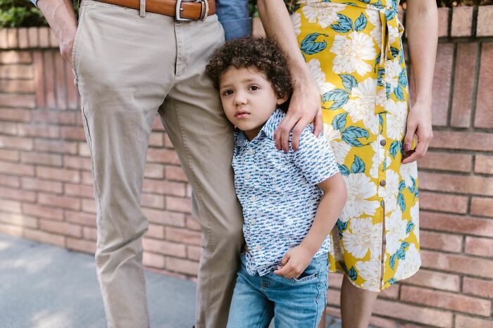 Sad young boy standing between his parents, representing family dynamics when men walk away from marriage