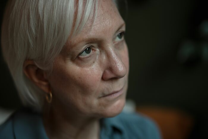 A thoughtful middle-aged woman looking up, carrying deep secrets she can never tell anyone in her real life.