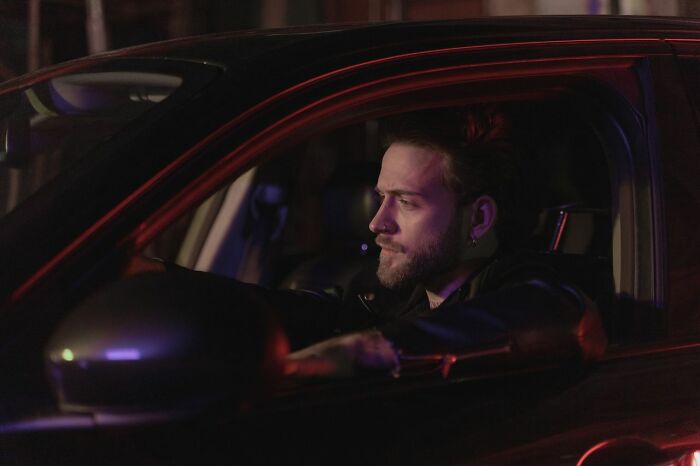 A concerned man driving his car at night, overwhelmed by an urgent feeling to leave immediately