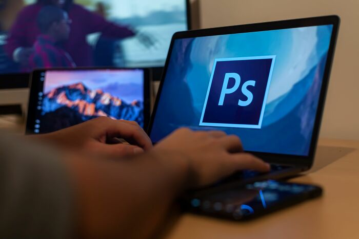 Person using Adobe Photoshop on a laptop representing companies people refuse to give money to