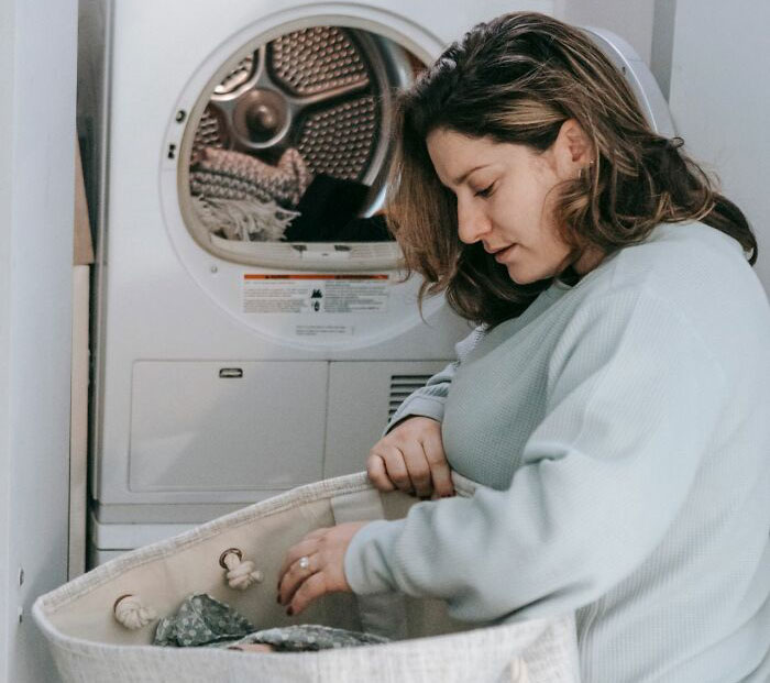 Woman loading laundry into dryer demonstrating helpful life hacks