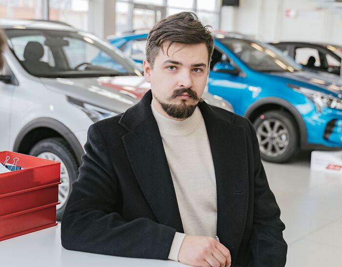 Man in a car dealership setting, reflecting on microaggressions women encounter