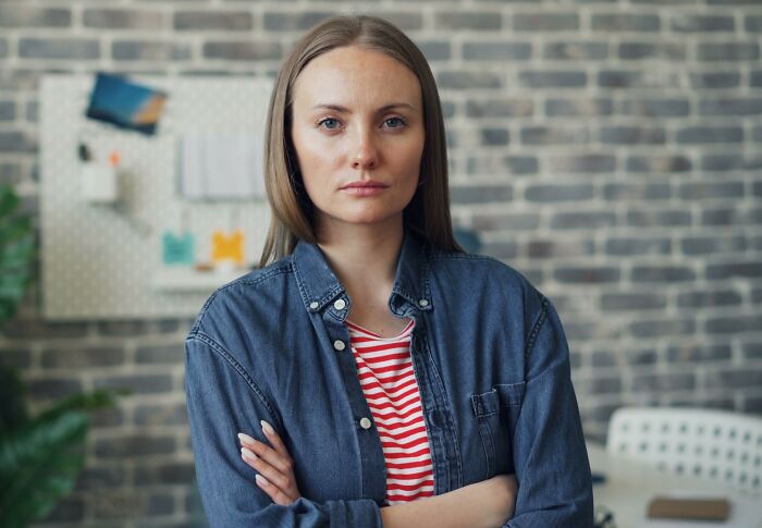 A serious woman standing with arms crossed, guarding personal secrets.