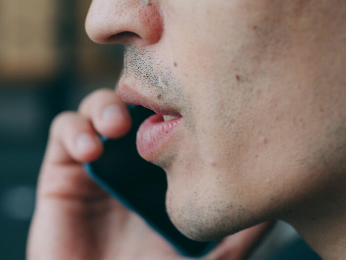 Close-up of a man speaking into his phone, sending a bizarre voice message