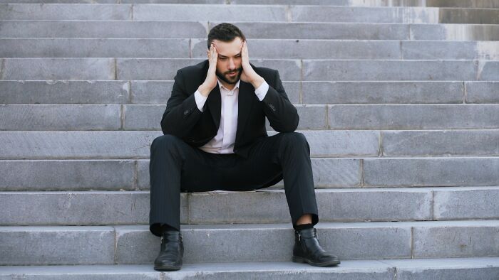 Stressed man sitting on concrete steps holding his head, contemplating why men walk away from marriage