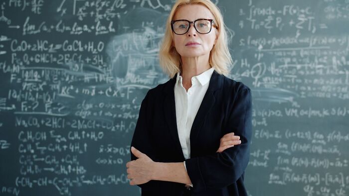 Blonde teacher standing before a chalkboard, context of satisfying revenge stories.