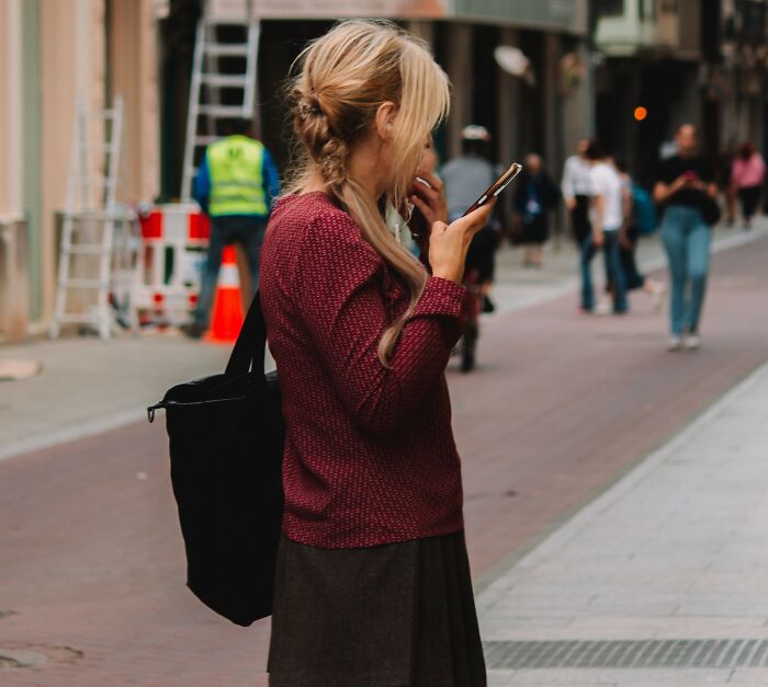 A woman looking at her phone on a city street, illustrating chilling stories of gut feelings.