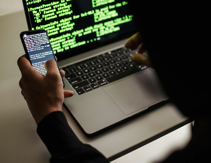A person using a laptop and phone, representing the exposure of women's private info by a Florida demonologist A person using a laptop and phone, representing the exposure of women's private info by a Florida demonologist