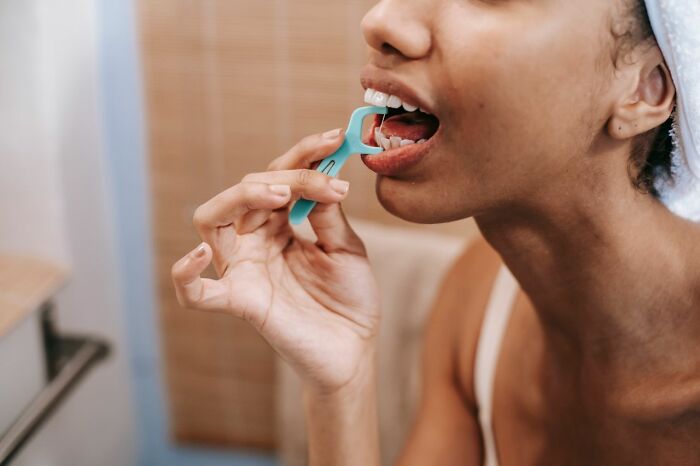 Person flossing teeth with dental floss pick featuring oral care life hacks